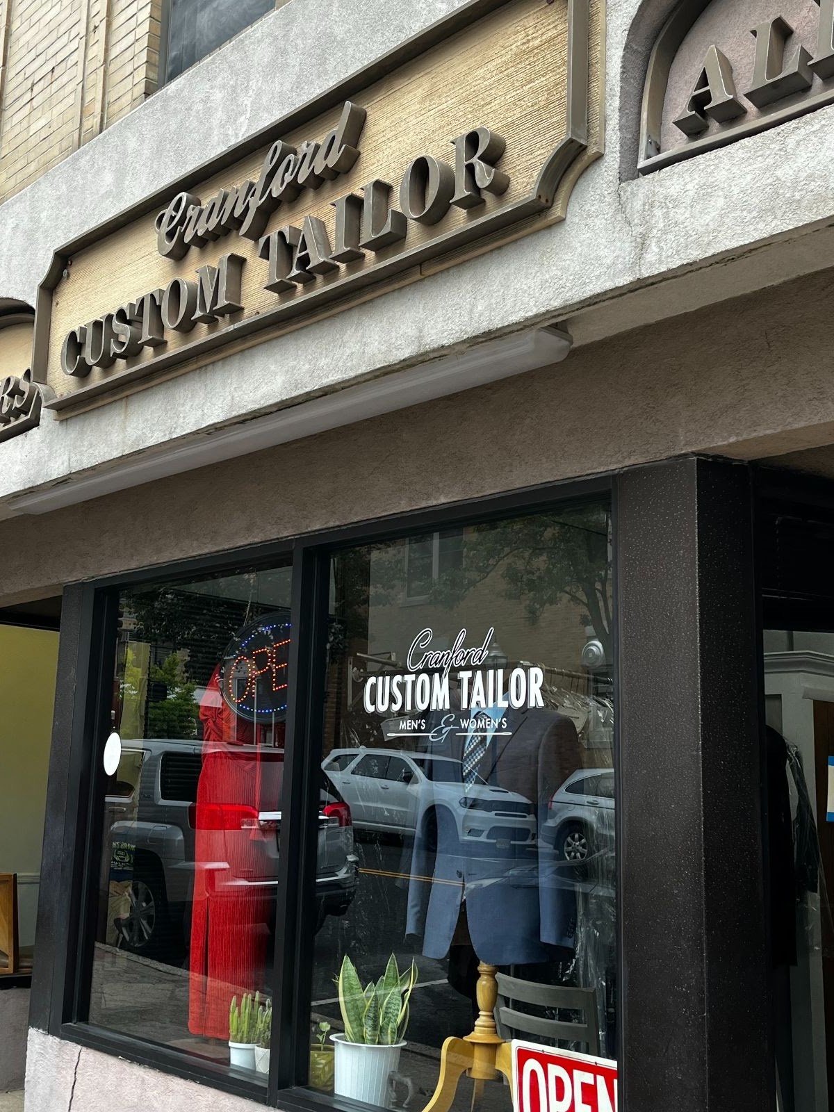 The Cranford Custom Tailor storefront sign and window on Alden Street, with a suit and a red dress on display